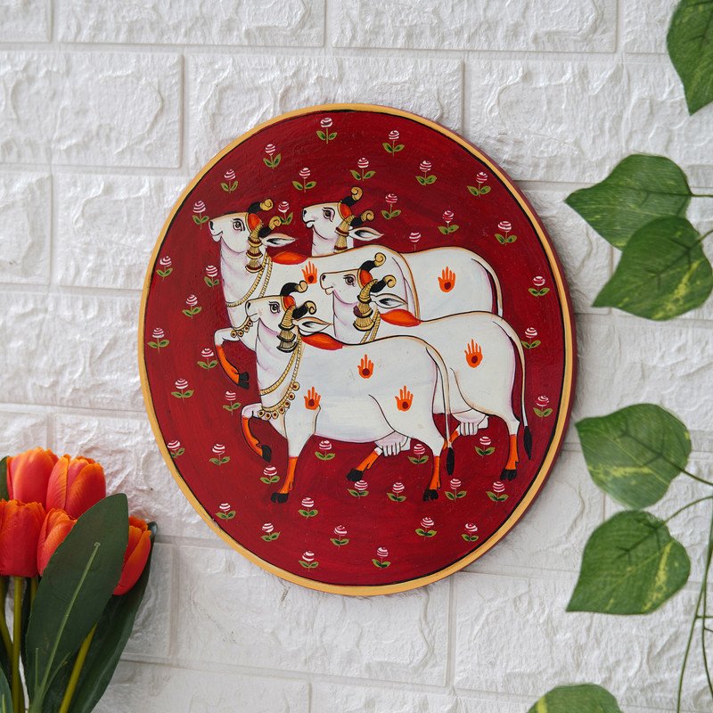 Crafted on a red plate, this pichwai portrays an enchanted encounter between a playful cow and a delicate lotus flower.