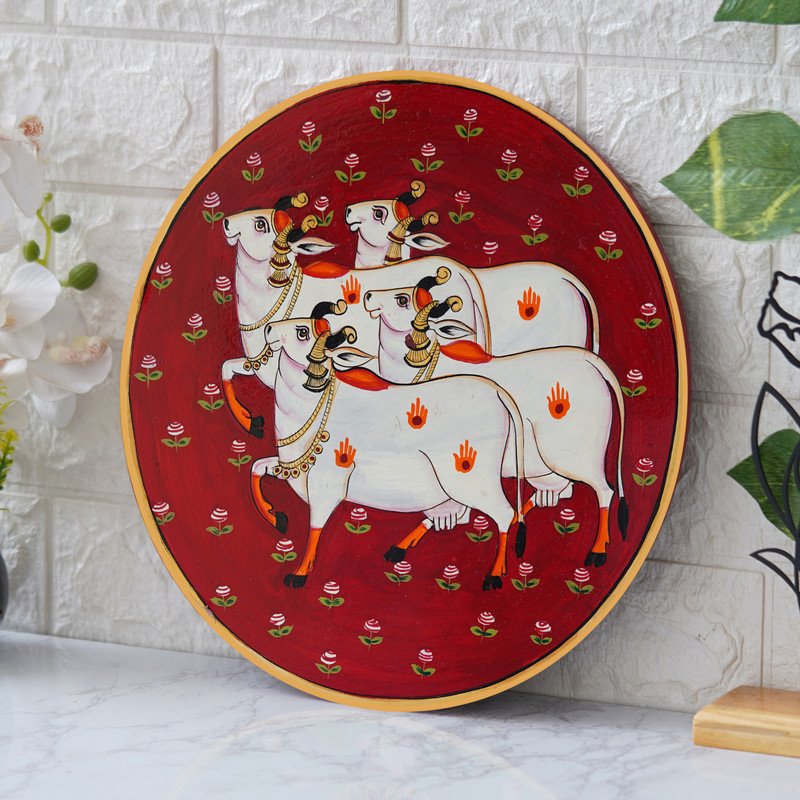 Crafted on a red plate, this pichwai portrays an enchanted encounter between a playful cow and a delicate lotus flower.