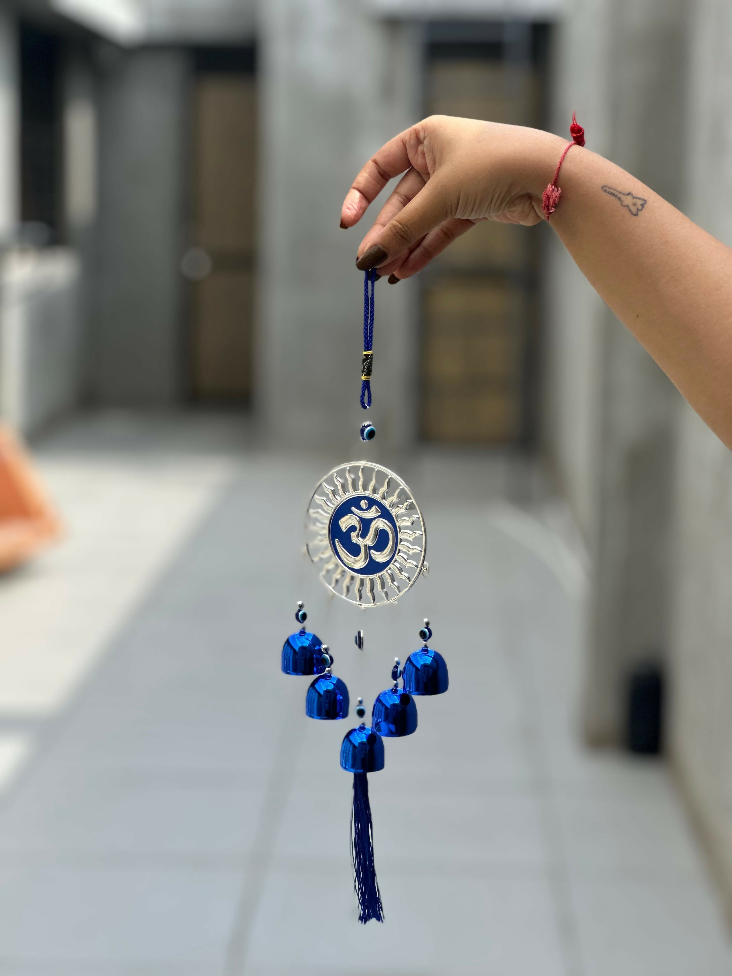 Spiritual Om Wall Hanging with Sun Design and Evil Eye Charms – Blue Metal Decorative Bell Wind Chime with Tassels for Positive Energy, Protection, and Home Vastu – Ideal for Home, Office, Balcony, or Gift Use
