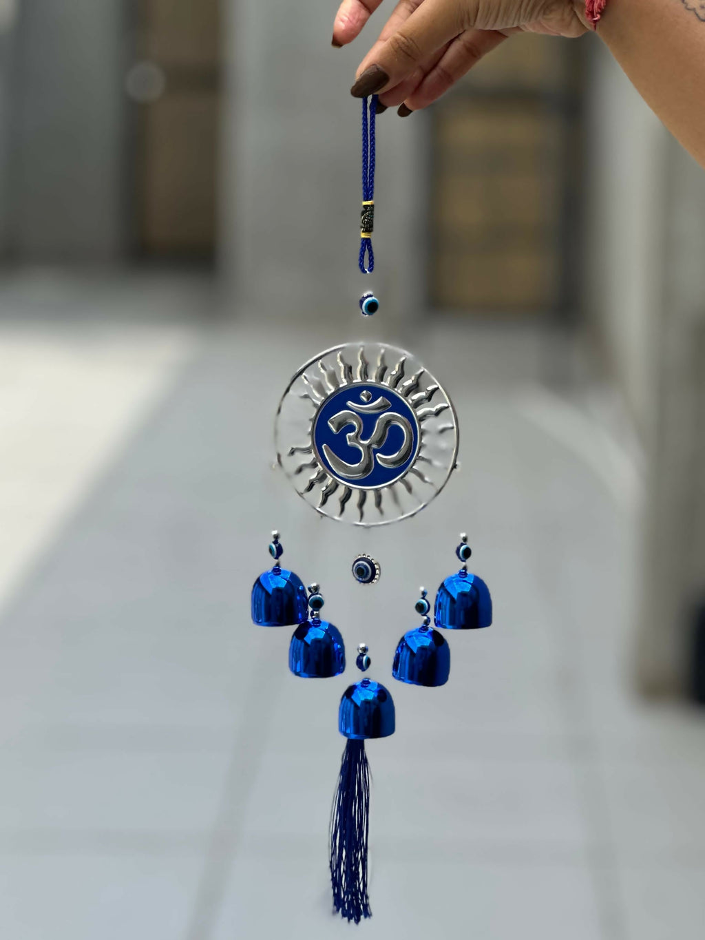 Spiritual Om Wall Hanging with Sun Design and Evil Eye Charms – Blue Metal Decorative Bell Wind Chime with Tassels for Positive Energy, Protection, and Home Vastu – Ideal for Home, Office, Balcony, or Gift Use